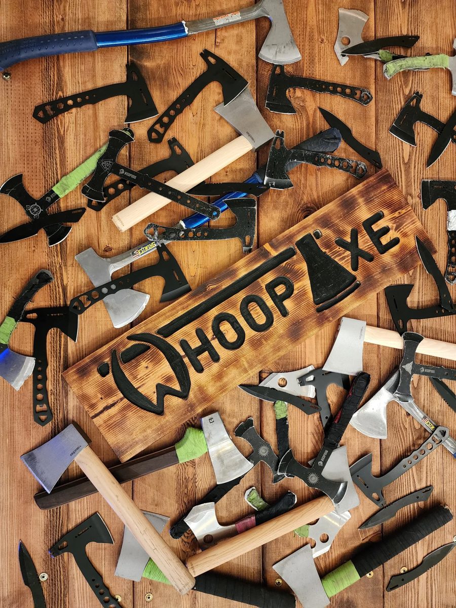 Throwing axes laid out around the Whoop Axe sign