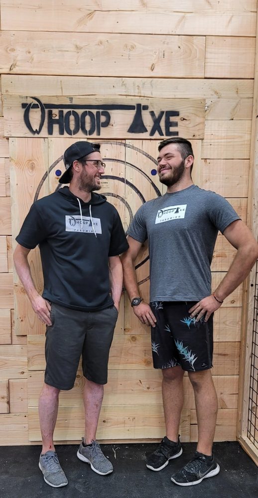 The Whoop Axe owners in front of the venue logo