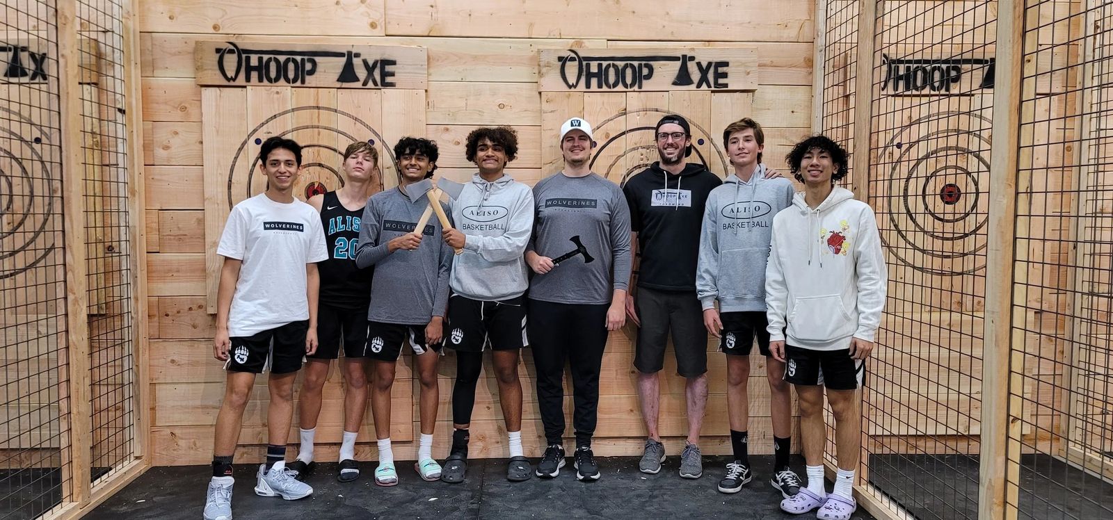 A team lined up in front of the Whoop Axe throwing cages and targets